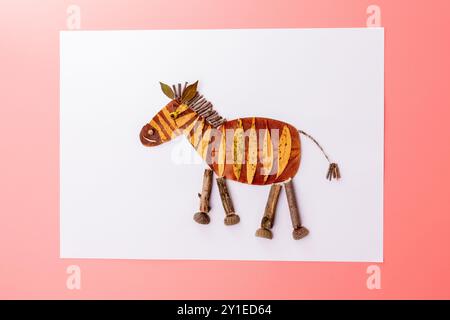 Kreativ gefertigte Figur eines Tierzebras aus natürlichen Materialien. Gelbe und braune Streifen imitieren das Zebramuster. Mähne und Schwanz aus getrocknetem Plan Stockfoto