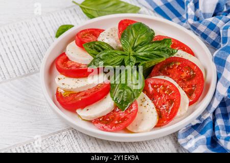 Eine lebendige und appetitliche Präsentation von Caprese Antipasti mit Scheiben reifer Gartentomaten, frischem Mozzarella und aromatischen Basilikumblättern Stockfoto