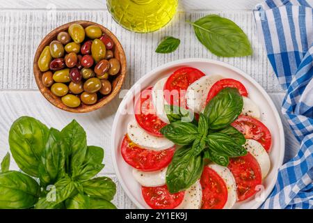 Eine lebendige und appetitliche Präsentation von Caprese Antipasti mit Scheiben reifer Gartentomaten, frischem Mozzarella und aromatischen Basilikumblättern Stockfoto