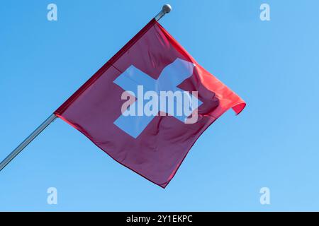 Die Schweizer Flagge weht im Wind gegen einen blauen Himmel. Genf, Schweiz Stockfoto