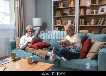 Lebensziele Seniorenpaar Mann und Frau im Ruhestand genießen ihr Leben zu Hause, verwenden Laptop-Computer und lesen Bücher, entspannen, Musik hören oder po Stockfoto
