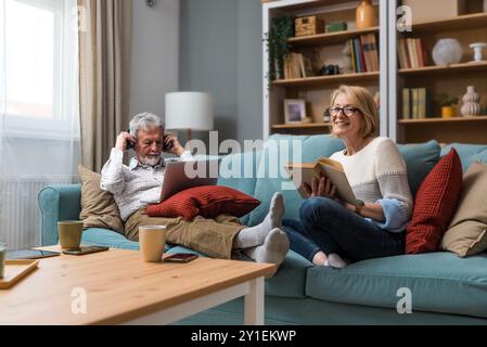 Lebensziele Seniorenpaar Mann und Frau im Ruhestand genießen ihr Leben zu Hause, verwenden Laptop-Computer und lesen Bücher, entspannen, Musik hören oder po Stockfoto