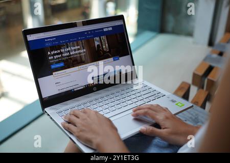 In dieser Fotoabbildung durchsucht eine Frau auf ihrem Laptop die Website Booking.com und überprüft den Preis für Flugticket und Hotel. Stockfoto