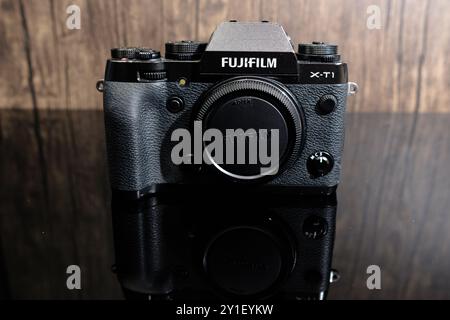 Newcastle UK: 19. Juni 2024: Kamera Fujifilm X-T1 mit einem schwarzen Körper auf einer reflektierenden Oberfläche vor einem hölzernen Hintergrund in einem gut beleuchteten Studio-Set Stockfoto