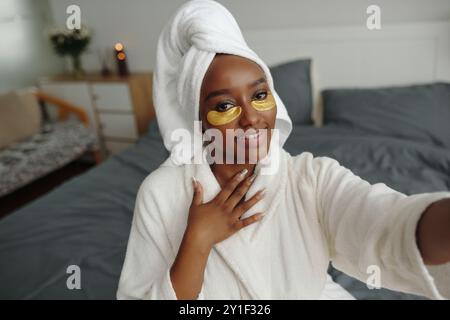 Tragen Sie Gesichtsmaske und Handtuch Turban während der Selfie-Einnahme Stockfoto