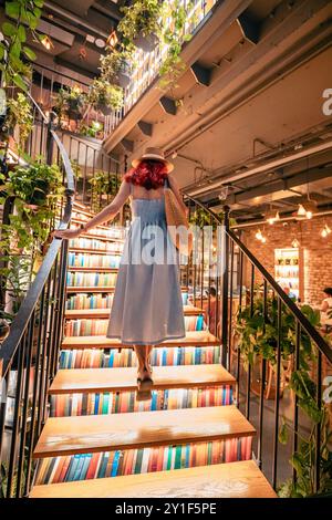 9. Juli 2024, Istanbul, Türkei: Frau auf der Treppe eines gemütlichen Buchhandlung Cafés Minoa Pera, umgeben von Regalen mit Vintage-Büchern, die ein W Stockfoto