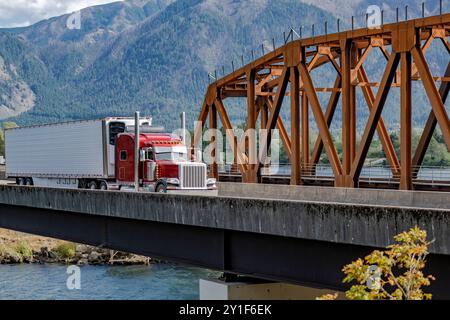 Klassischer roter großer Lkw-Sattelzugmaschine mit langer Fahrerkabine für den Transport von Fracht im Kühlschrank, Auflieger, der auf der Fahrerkabine läuft Stockfoto