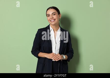 Schöne Frau im schwarz gestreiften Anzug auf grünem Hintergrund Stockfoto