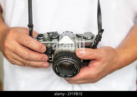 London. UK- 09.03.2024.Eine Person, die eine Olymp-Kamera trägt und hält, eine Spiegelreflexkamera mit Filmnegativen. Stockfoto