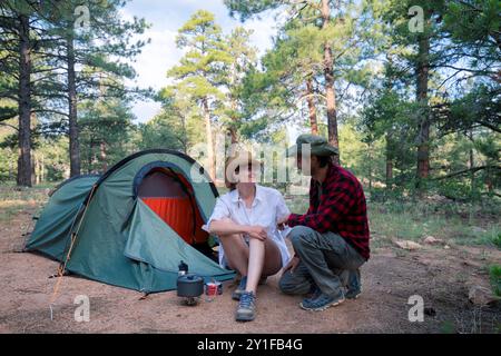 Glückliches Paar, das die Aussicht genießt, während es im Wald campt Stockfoto