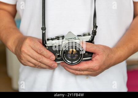 London. UK- 09.03.2024. Eine Person, die eine Olymp-Kamera trägt, eine Spiegelreflexkamera mit Filmnegativen. Stockfoto