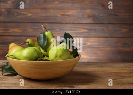 Frische grüne Birnen und Blätter in der Schüssel auf Holztisch. Leerzeichen für Text Stockfoto