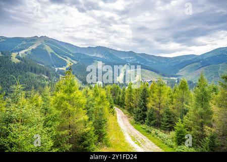 Das Jasna Mountain Resort liegt unter dem Berg Chopok und bietet einen atemberaubenden Blick auf üppige Wälder und schneebedeckte Gipfel, perfekt für Outdoor-Aktivitäten das ganze Jahr über im Demanovska-Tal, Slowakei. Stockfoto