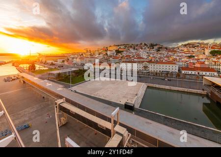 Blick auf den Sonnenuntergang von einem Kreuzfahrtschiff am Hafen von Lisboa auf die Skyline der Stadt, den Fluss Tejo und die Brücke Ponte 25 de Abril in Lissabon, Portugal. Stockfoto