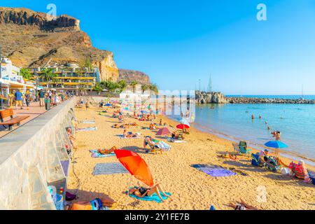 Ein sonniger Tag am Sandstrand Playa Mogan und der Promenade mit Cafés im beliebten Fischerdorf Puerto de Mogan auf Gran Canaria, Spanien. Stockfoto