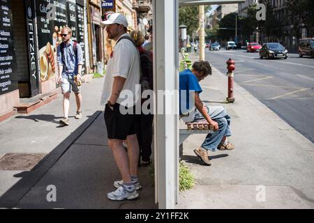 Ein Obdachloser sitzt auf einer Bank an einer Bushaltestelle in Budapest. Stockfoto