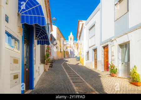 Der Glockenturm der Kirche San Sebastian aus der Kopfsteinpflasterstraße Rua dos Ferreiros in der historischen Altstadt von Lagos, Portugal. Stockfoto