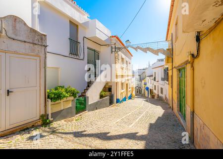 Eine Wohnstraße am Hang, die in die Altstadt in der historischen weiß getünchten Küstenstadt Lagos in der Algarve im Süden Portugals führt. Stockfoto