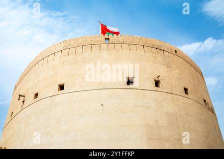 Hauptturm der arabischen Zitadelle Nizwa mit omanischer Flagge, die oben weht, Nizwa, Sultanat Oman Stockfoto