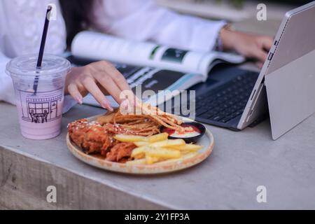 Schöne asiatische Frau im Büro im Café im Freien. Lächelndes Mädchen beim Essen während der Arbeit für Inhalte oder Werbung Stockfoto