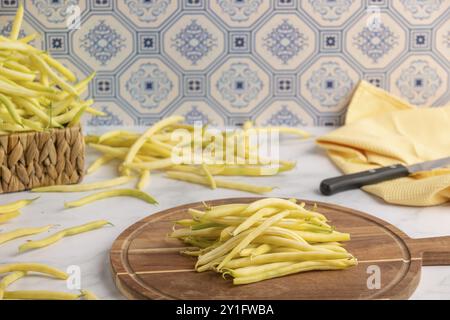 Ein Haufen gelbe Bohnen auf einem hölzernen Schneidebrett mit einem Messer an der Seite Stockfoto