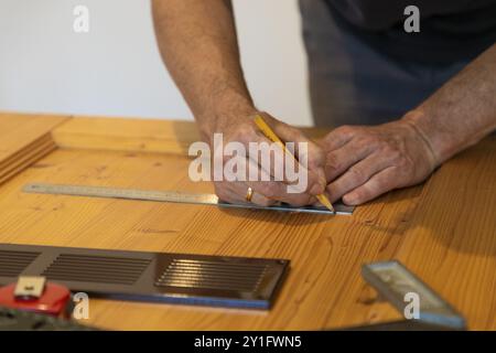 Die Hände zeichnen vorsichtig mit einem Lineal und Bleistift in Nahaufnahme auf Holz Stockfoto