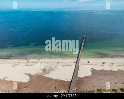 Blick aus der Vogelperspektive auf einen langen schmalen Steg über einem weißen Sandstrand und das Meer in Kingston SE an der Limestaone Coast in Australien Stockfoto