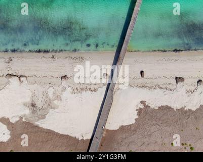 Blick aus der Vogelperspektive auf einen langen schmalen Steg über einem weißen Sandstrand und das Meer in Kingston SE an der Limestaone Coast in Australien Stockfoto