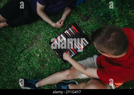 Zwei Freunde genießen ein Spiel Backgammon auf dem Gras Stockfoto