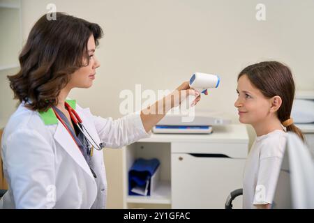 Der Kinderarzt misst die Temperatur des Patienten mit einem berührungslosen Thermometer Stockfoto