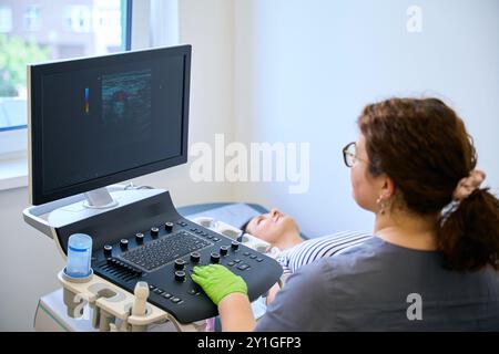 Ultraschallspezialist führt eine Ultraschalluntersuchung bei einem Patienten mittleren Alters durch Stockfoto