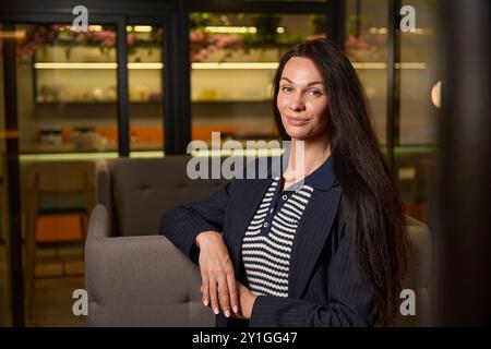 Junge schöne Frau sitzt im Entspannungsbereich des Coworking Space Stockfoto