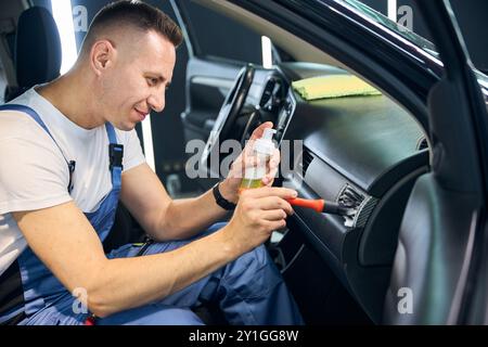 Der Typ reinigt die Lüftungslöcher im Inneren des Autos Stockfoto