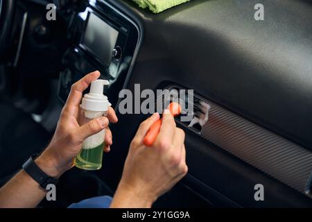 Der Mann reinigt die Lüftungslöcher im Innenraum des Autos Stockfoto