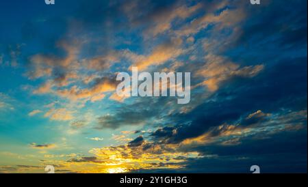 Tropischer Sonnenuntergang. Wunderschöner Sonnenuntergangshimmel mit Wolken. Himmelblaues und orangefarbenes Licht der Sonne durch die Wolken am Himmel. Hintergrund dunkler Wolken vor St. Stockfoto