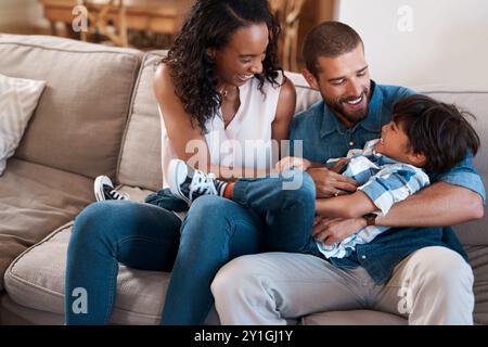 Familie, spielendes und kitzelndes Kind zu Hause, lustige Spiele und Goofy Bonding für Liebesbeziehung. Eltern, Sohn und Kind zum Glück im Wohnzimmer Stockfoto