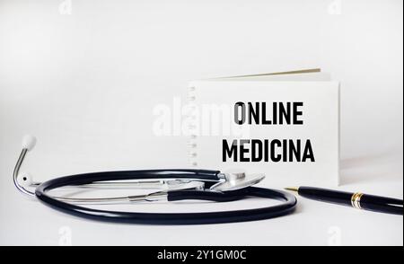 Stethoskop und Notizblock auf weißem Hintergrund mit der Inschrift Online Medicine. Stockfoto