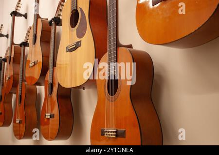 Nahaufnahme mehrerer spanischer Gitarren, die an der Wand hängen, nach einem Musikkurs Stockfoto