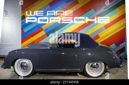 Der graue Porsche 356 im petersen Automobilmuseum in Los angeles mit einer bunten gestreiften Wand ist der porsche-Schriftzug im Hintergrund. Stockfoto