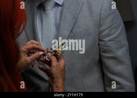 Die unerkennbare Frau zieht die Boutonniere des Bräutigams an, Spanien Stockfoto