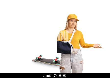 Junge Frau mit Skateboard und gebrochenem Arm, die eine Armschiene auf weißem Hintergrund trägt Stockfoto