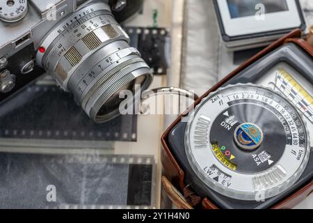 Nahaufnahme eines Lichtmessers für die Vintage-Fotografie und einer Vintage-Kamera auf einem Ordner mit Filmnegativen und Dias. Stockfoto