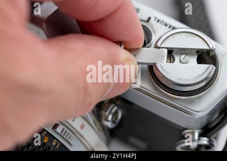Nahaufnahme einer Person, die den Hebel zum Zurückspulen der Filmrolle einer alten Spiegelreflexkamera verwendet. Stockfoto