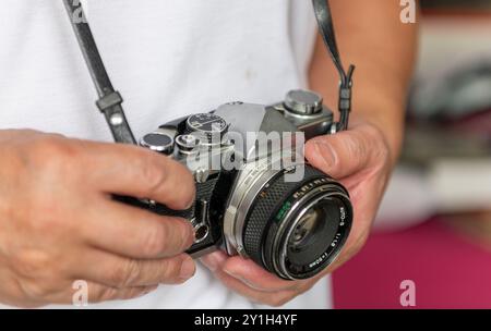 Eine Person, die eine klassische Spiegelreflexkamera mit Kamera in der Hand hält. Stockfoto