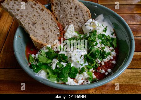 Shakshouka pochierte Eier in einer scharfen Tomatensauce mit Fetakäse, Koriander und frischem Brot, ein maghrebisches Brakfast-Gericht Stockfoto