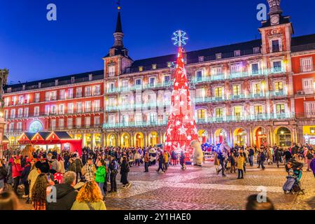 Madrid, Spanien - 18. Dezember 2023. Bei Einbruch der Dunkelheit versammelt sich die festliche Menge auf der Plaza Mayor, beleuchtet von einem strahlenden Weihnachtsbaum mit der Hauptfassade Stockfoto