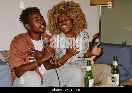 Glückliche alte Freunde genießen Karaoke, während sie zu Hause zusammen abhängen Stockfoto