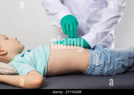 Ein Gastroenterologe palpiert den Bauch eines siebenjährigen Mädchens. Bauchschmerzen bei Kindern. Erkrankungen der Milz und des Pankreas, Pankreatit Stockfoto