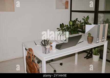 Bürobedarf und schwarzer Laptop auf weißem Holztisch zu Hause Stockfoto
