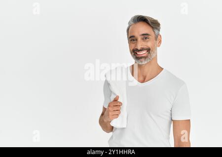 Glücklicher Mann mittleren Alters, der ein Duschtuch auf weißem Studiohintergrund hält. Stockfoto